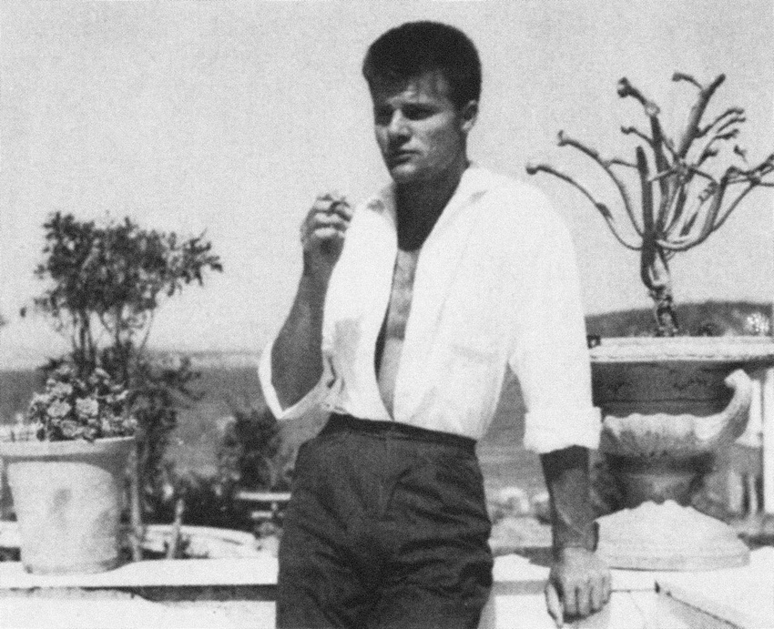 Auf dem Schwarzweiß-Foto ist Günter Schwannecke im Urlaub auf Ischia im Jahr 1958 zu sehen. Er ist damals etwa 25 Jahre alt. Er steht lässig auf einem Balkon zwischen zwei Topfpflanzen. Er trät eine dunkle Stoffhose, die bsi weit über die Hüften sitzt und ein weißes, offenes Hemd, das in die Hose gestekct ist. Mit der linken Hand stützt er sich auf ein Geländer auf, in der rechten Hand hält er eine Zigarette. Er hat einen Kurzhaarschnitt. Im Hintergrund ist eine Landschaft zu sehen.